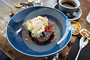 Brownie cake with salted caramel. Anglaise foam, raspberry sauce, praline nut and fresh berry. Delicious sweet dessert