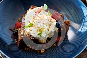 Brownie cake with salted caramel. Anglaise foam, raspberry sauce, praline nut and fresh berry. Delicious sweet dessert