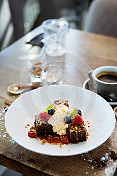 Brownie cake with salted caramel. Anglaise foam, raspberry sauce, praline nut and fresh berry. Delicious sweet dessert