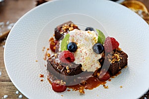 Brownie cake with salted caramel. Anglaise foam, raspberry sauce, praline nut and fresh berry. Delicious sweet dessert