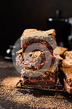 Brownie cheesecake cake with cherry and chocolate on dark background.