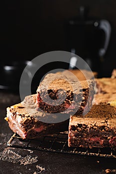 Brownie cheesecake cake with cherry and chocolate on a dark background. Selective focus