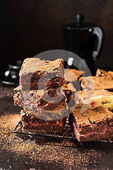 Brownie cheesecake cake with cherry and chocolate on a dark background. Selective focus