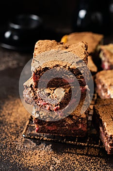 Brownie cheesecake cake with cherry and chocolate on a dark background. Selective focus