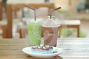 Brownie chocolate cake have marshmallow, almond, chocolate- chip on topping and have fork beside on white dish and soft drink