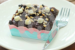 Brownie chocolate cake have marshmallow, almond, chocolate- chip on topping on white dish