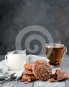 Brownie cookies on a wooden table with tea and milk. Copy space