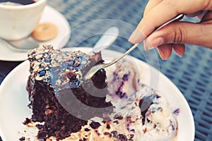 Brownie with icecream. sweet and dessert. female hand with a spoon separates a piece of cake