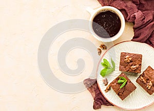 Brownie sweet chocolate dessert with walnuts and meant leaves on craft plate and cup of black coffee.