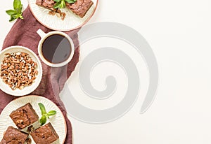 Brownie sweet chocolate dessert with walnuts and meant leaves on craft plate and cup of black coffee.