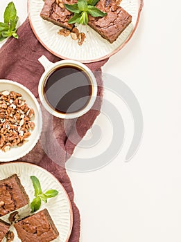 Brownie sweet chocolate dessert with walnuts and meant leaves on craft plate and cup of black coffee.