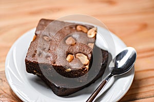 Brownies cake on the table - chocolate cake slice with nut in the plate with spoon on wooden background