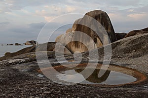 Brownish rock and a puddle with cloudy sky