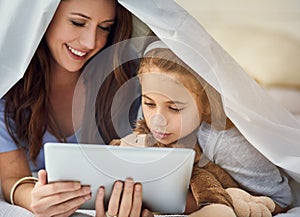 Browsing in bed. a mother and her daughter using a digital tablet.