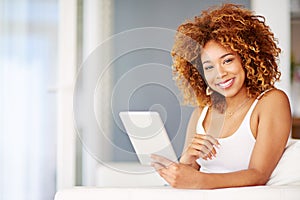 Browsing an online library for the perfect weekend read. Portrait of a young woman using a digital tablet on the sofa at