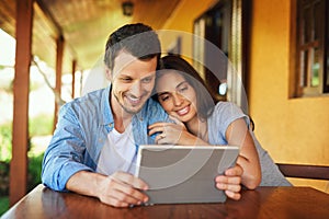 Browsing time is bonding time. Shot of a young couple using a digital tablet together outdoors.