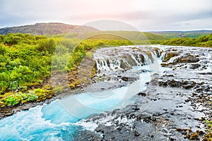 Bruarfoss waterfall with blue water at sunset.