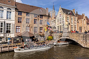 Bruges, Belgium - APRIL 05, 2019: Tour boat taking tourists through the beautiful city of Bruges by the canal