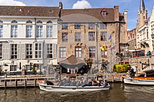 Bruges, Belgium - APRIL 05, 2019: Tour boat taking tourists through the beautiful city of Bruges by the canal