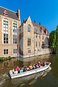 BRUGES, BELGIUM - APRIL 6, 2008: Tourists float on a boat through the Dijver channel