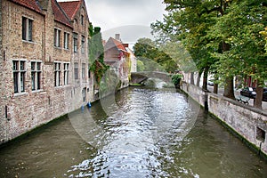 BRUGES, BELGIUM - SEPTEMBER 05, 2018: Canal in Bruges and famous Belfry tower on the background in a beautiful autumn day, Belgium