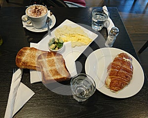 Brunch indoor restaurant mocha coffee and eggs with toast and vegetales and cheese croissant tasty food still life photo