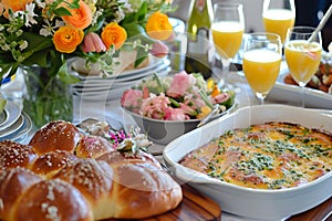 A brunch table boasts fresh pastries, quiche, and mimosas with a vibrant floral centerpiece. The setting is perfect for