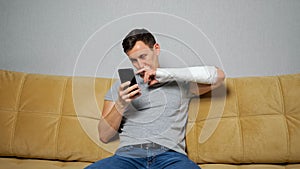 Brunet man picks nose with broken arm scrolling social media