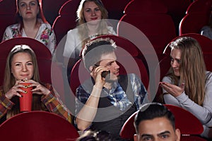 Brunet man talking at call phone at cinema hall.