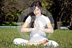 Brunet yoga girl on green grass in park.