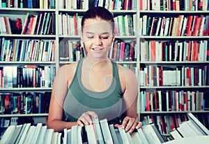 Brunete girl chooses a book in university library