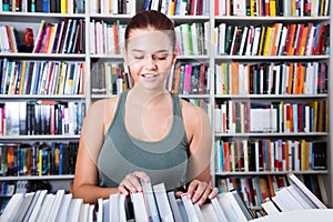 Brunete girl chooses a book in university library