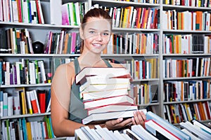 Brunete girl chose a lot of books in university library