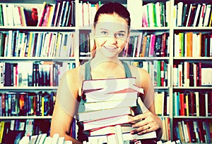Brunete girl chose a lot of books in university library