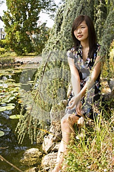 Brunette asian girl sitting at the lakeside.