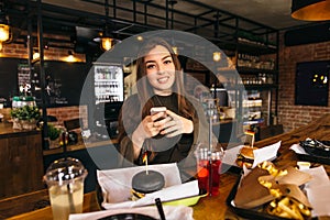 Brunette Asian woman sitting at the bar with cocktail in luxury interior.