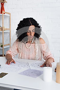 brunette astrologist near natal charts and photo