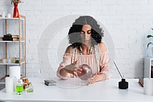 brunette astrologist touching magic sphere near photo