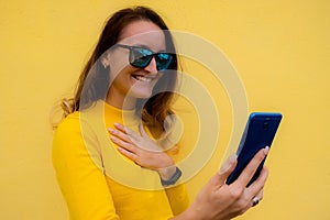 Brunette beautiful happy woman using smart phone. Excited surprised girl texting on her mobile phone. Technology