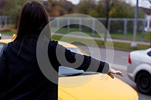 Brunette in black dress standing back stops yellow taxi