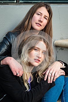 Brunette and blonde girls sitting on stairs in an urban environment