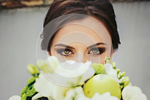 Brunette bride with magic green eyes looks over a green wedding