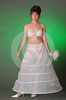 brunette bride in the morning in bra, crinoline and wedding bouquet in hand, preparing