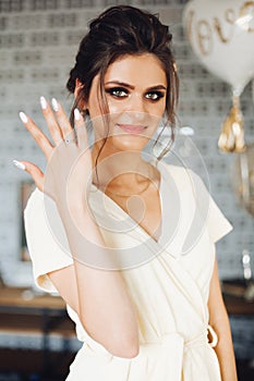 Brunette bride showing hand with wedding ring and hiding face.