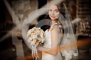 Brunette bride smiling and holding wedding bouquet of roses