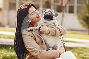 Brunette in a brown coat walks with pug