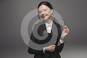 Brunette businesswoman in black suit holding diary and smiling at camera