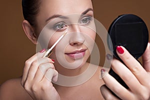 Brunette caucasian woman apply concealer under her eyes. Flawless clean skin. Beauty skin care concept