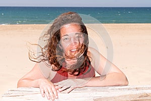 Brunette cheery happy pleased gorgeous attractive woman lying outdoors at sea beach in summer wind