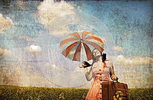 Brunette enchantress with umbrella and suitcase